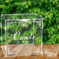 a clear acrylic box sitting on top of a wooden table next to green leaves