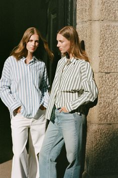 two women standing next to each other in front of a building with their hands on their hips