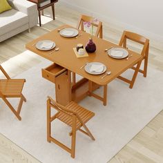 a wooden table with chairs and plates on it in a room next to a couch