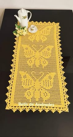 a table with a yellow doily on it and a white tea pot next to it