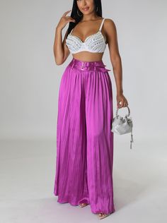 a woman in a white bra top and purple pleated pants posing for the camera