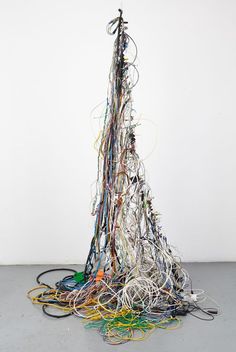 a pile of wires sitting on top of a gray floor next to a white wall