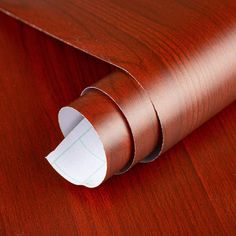 a roll of white paper on top of a wooden table with red wood grained finish