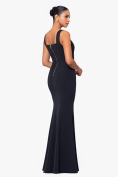 a woman in a long black dress is looking back at the camera and she has her hand on her hip