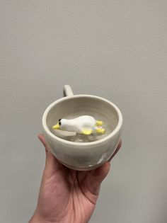 a hand holding a white ceramic bowl with a black and yellow dog in the center