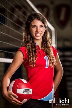 a woman in red shirt holding a volleyball ball