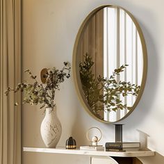 a mirror sitting on top of a table next to a vase with flowers in it