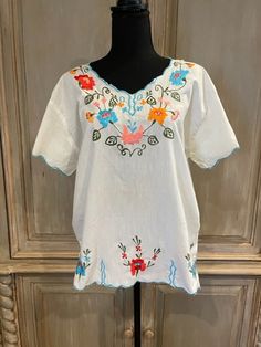 Cute Mexican embroidered top! Vibrant  flowers in orange, red and blue on a dark green vine surround the neckline and continue down the bodice. The same design can be found on the sleeves and edging the  bottom. The same areas have a turquoise embroidered edge. The size is estimated to be a ladies M.  The garment is in perfect condition, showing no signs of wear.  I do not make exchanges or accept returns.  Don't hesitate to contact me with questions! Embroidered Edge, Lady M, Vibrant Flowers, Embroidered Tunic, Vibrant Flower, Embroidered Top, Orange Red, Womens Clothing Tops, Dark Green