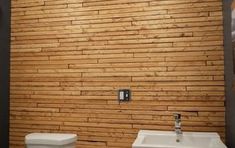 two white toilets sitting next to each other in a room with wooden walls and flooring