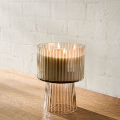 a glass candle holder sitting on top of a wooden table