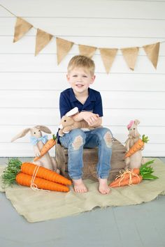 a young boy sitting on a crate with carrots and bunnies in front of him