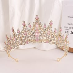 a tiara with pink and white stones on it sits next to a sign that reads,