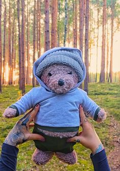 a person holding a teddy bear in the woods