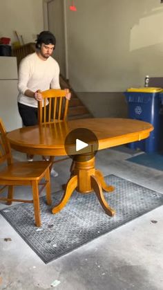 a man standing next to a wooden table and chair in a room with an area rug on the floor