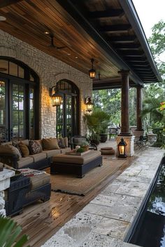 an outdoor living area with couches and lamps on the side of the house next to a pond