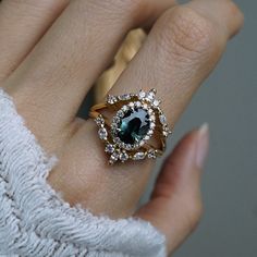 a woman's hand wearing a ring with an oval shaped blue and white stone