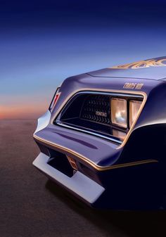 the rear end of a blue muscle car with gold lettering on it's hood