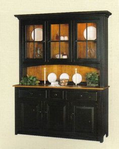 a black china cabinet with glass doors and two candles on the top, in front of a white background