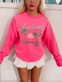 The Charleston Crewneck from Sassy Shortcake is a hot pink preppy sweatshirt. She features a beachy scene with green palm trees and the text "Charleston South Carolina" in white and green. She is soft, lightweight, and absolutely adorable! Oversized fit + unisex sizing. Model is wearing a size small. Trendy Spring Beach Sweatshirt, Trendy Sweatshirt For Beach In Spring, Spring Beach Cotton Sweatshirt, Spring Beach Long Sleeve Sweatshirt, Spring Long Sleeve Sweatshirt For Beach, Summer Vacation Sweatshirt With Letter Print, Casual Pink Beach Sweatshirt, Pink Cotton Top With Palm Tree Print, Pink Summer Vacation Sweatshirt