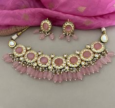 This beautiful pink kundan necklace set with earrings to match has great artistry and will add charm to your attire. It is embedded with kundan and pink stones. The dangling pink beads add a classic sparkle.  Details: Necklace Width-2 Inches Earrings Length-2 Inches Weight of Each Earring-14 gms All products are manufactured using traditional skills from our rich heritage of crafts.  The process of these crafts is essentially manual. Hence, any irregularities or variations are an inherent part of these handcrafting processes. Pink Traditional Necklace With Stone Work, Traditional Pink Necklaces For Festivals, Traditional Pink Necklace With Stone Work, Traditional Pink Stone Work Necklaces, Pink Round Jewelry Sets For Diwali, Pink Meenakari Necklaces For Festivals, Pink Meenakari Necklace For Festivals, Festive Pink Meenakari Necklace, Pink Kundan Necklace For Festivals