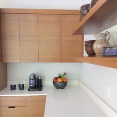 a bowl of fruit sits on the counter in a kitchen with wooden cabinets and white counters