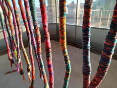 there are many colorful yarns hanging from the ceiling in this room with large windows