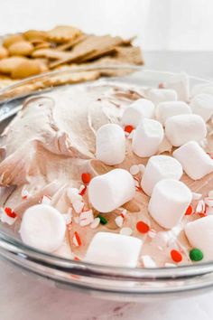 a bowl filled with marshmallows on top of a table next to crackers