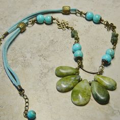 "Graduated size olive green new jade tear drop shaped beads are linked in antique brass wire accented with antique brass beads. The length of the necklace features turquoise magnesite beaded links, green serpentine beaded links and antique brass Celtic knot filigree. Beaded segments are linked on aqua blue suede cording accented with antique brass beads. There is a lobster claw closure on the necklace. Great casual rustic look. The length of the necklace is 21\" with a 1 1/2\" extension chain fo Green Teardrop Turquoise Bohemian Necklace, Adjustable Bohemian Jade Jewelry, Turquoise Jade Beaded Bohemian Necklace, Bohemian Jewelry With Gemstone Beads Teardrop Pendant, Bohemian Turquoise Jade Beaded Necklaces, Turquoise Bohemian Jade Beaded Necklaces, Bohemian Jade Gemstone Beads Jewelry, Bohemian Teardrop Pendant Jewelry With Gemstone Beads, Turquoise Jade Bohemian Beaded Necklace