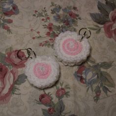 two crocheted keychains with pink and white flowers on a floral background