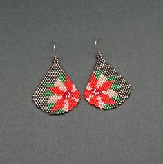 a pair of red and green beaded earrings on a gray surface with white dots