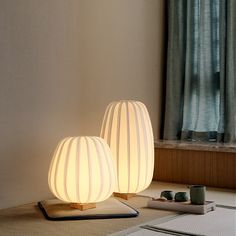 two lamps sitting next to each other on top of a rug in front of a window