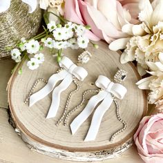 three pieces of jewelry sitting on top of a piece of wood with flowers in the background