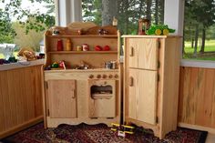 a wooden toy kitchen with lots of toys on the floor and in front of it