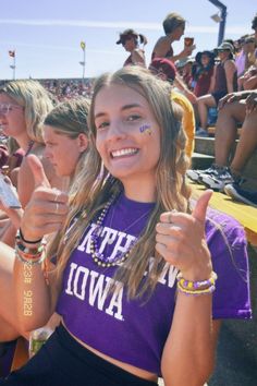 a girl in purple shirt giving the thumbs up