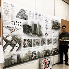 two men standing in front of a wall with architectural drawings on it and one holding a piece of paper