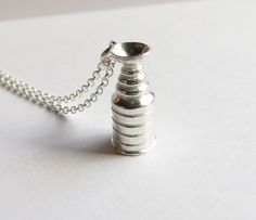 a small silver vase sitting on top of a white table next to a ball chain