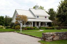 a large white house sitting on top of a lush green field next to a stone wall