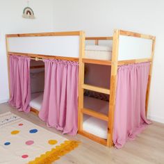 two bunk beds with pink curtains are next to each other in a room that has wooden floors and white walls