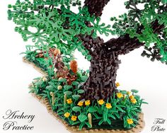 a lego model of a tree with people in the middle and flowers on the ground