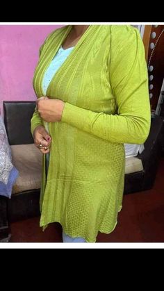 a woman standing in front of a couch wearing a green cardigan