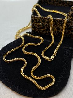 a gold chain is laying on top of a black case