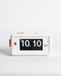 an orange and white alarm clock with the time 10 10 on it's face