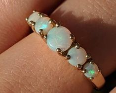 a woman's hand holding a ring with opal stones on it