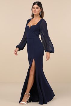 a woman in a blue gown with long sleeves and high slits, posing for the camera