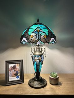 a lamp that is sitting on top of a table next to a potted plant