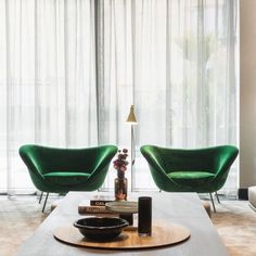 a living room with two green chairs and a coffee table in front of a window