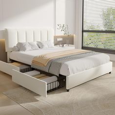 a white bed with drawers underneath it in a room next to a window and blinds