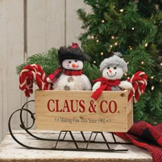 two snowmen sitting in a sleigh holding a sign that says claus & co