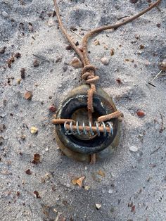 an old metal object is tied to a rope on the sand with shells around it