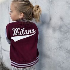 Custom kids unisex varsity sports jacket.  Personalised with the name (back) and number or letter (front) of your choice. ** Our varsity jackets fit true to size but we always recommend ordering a size bigger just to make sure ** Age / Size - Standard Universal Sizes * 6-12 Months / Length 13.5 inches / Chest 12 inches * 1-2 Years / Length 14 inches / Chest 13 inches * 2-3 Years / Length 15.5 inches / Chest 13.5 inches * 3-4 Years / Length 17 inches / Chest 15 inches * 5-6 Years / Length 18.5 inches / Chest 16 inches * 7-8 Years / Length 20 inches / Chest 17 inches * 9-11 Years / Length 22.5 inches / Chest 18 inches * 12-13 Years / Length 24 inches / Chest 19 inches * Made from soft heavyweight 330 gsm (approx) fabric. * 80% Cotton. 20% Polyester. * Contrast sleeves. * Knitted collar, cuff Team-colored Long Sleeve Varsity Jacket With Team Name, Varsity Jacket With Team Name For Game Day, Game Day Varsity Jacket With Team Name, Game Day Long Sleeve Varsity Jacket With Team Name, Team Spirit Varsity Jacket For Sports Events, Long Sleeve Varsity Jacket With Team Name For Sports, Varsity Jacket With Letter Patch, Varsity Jacket With Letter Patch And Long Sleeves, Sports Style Letter Print Varsity Jacket